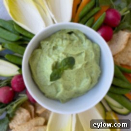 Close up of creamy basil and avocado dip in white bowl.