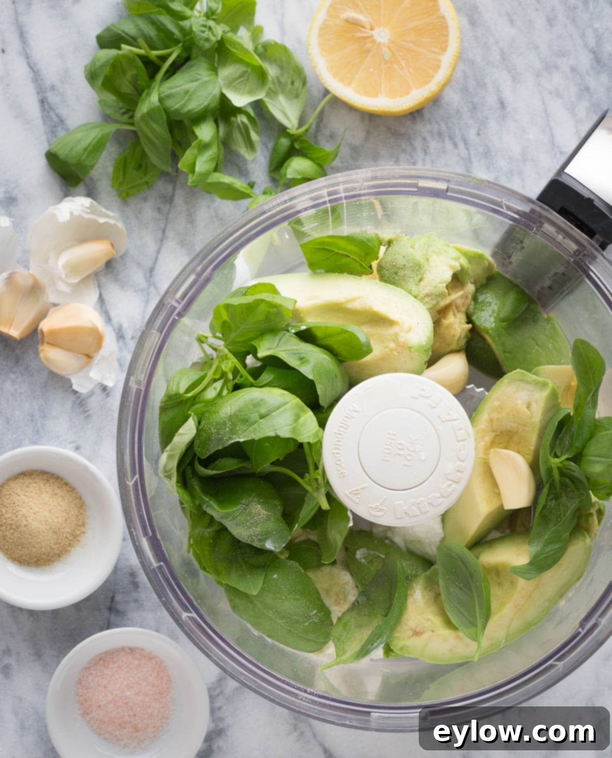 Creamy Avocado Basil Yogurt Dip 4 Avocados, basil leaves, lemon juice, and garlic in a food processor bowl for making dip.