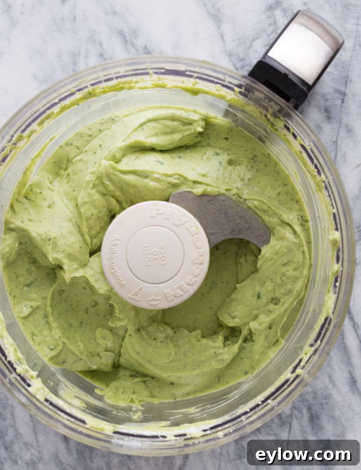 Creamy Avocado Basil Yogurt Dip 5 Creamy green avocado dip with flecks of basil leaves in a food processor.