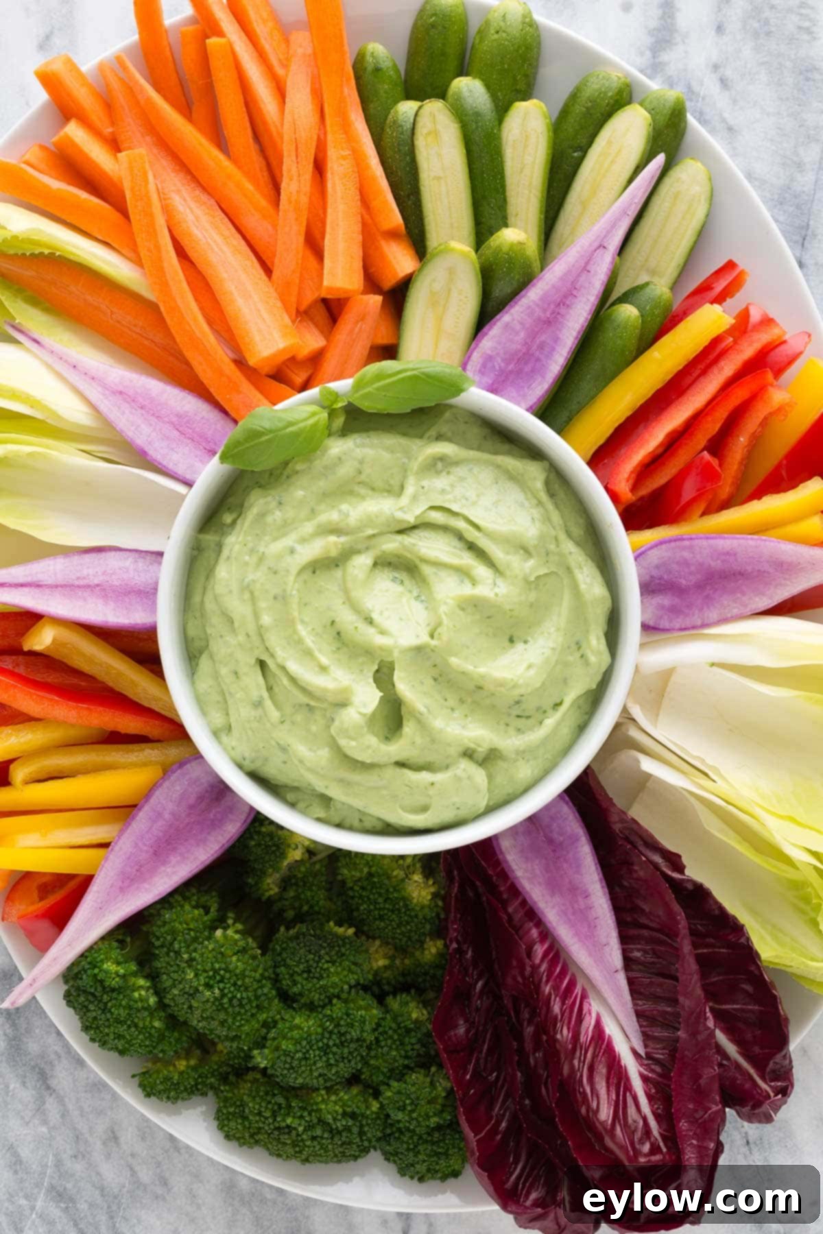 Creamy Avocado Basil Yogurt Dip 6 A platter of colorful veggies with carrots, red pepper, broccoli, radishes, and endive with avocado dip.