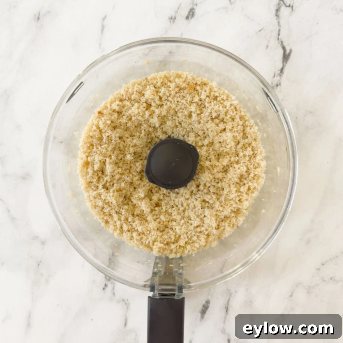 Bread cubes after being processed into fine crumbs in a food processor, demonstrating the desired consistency.