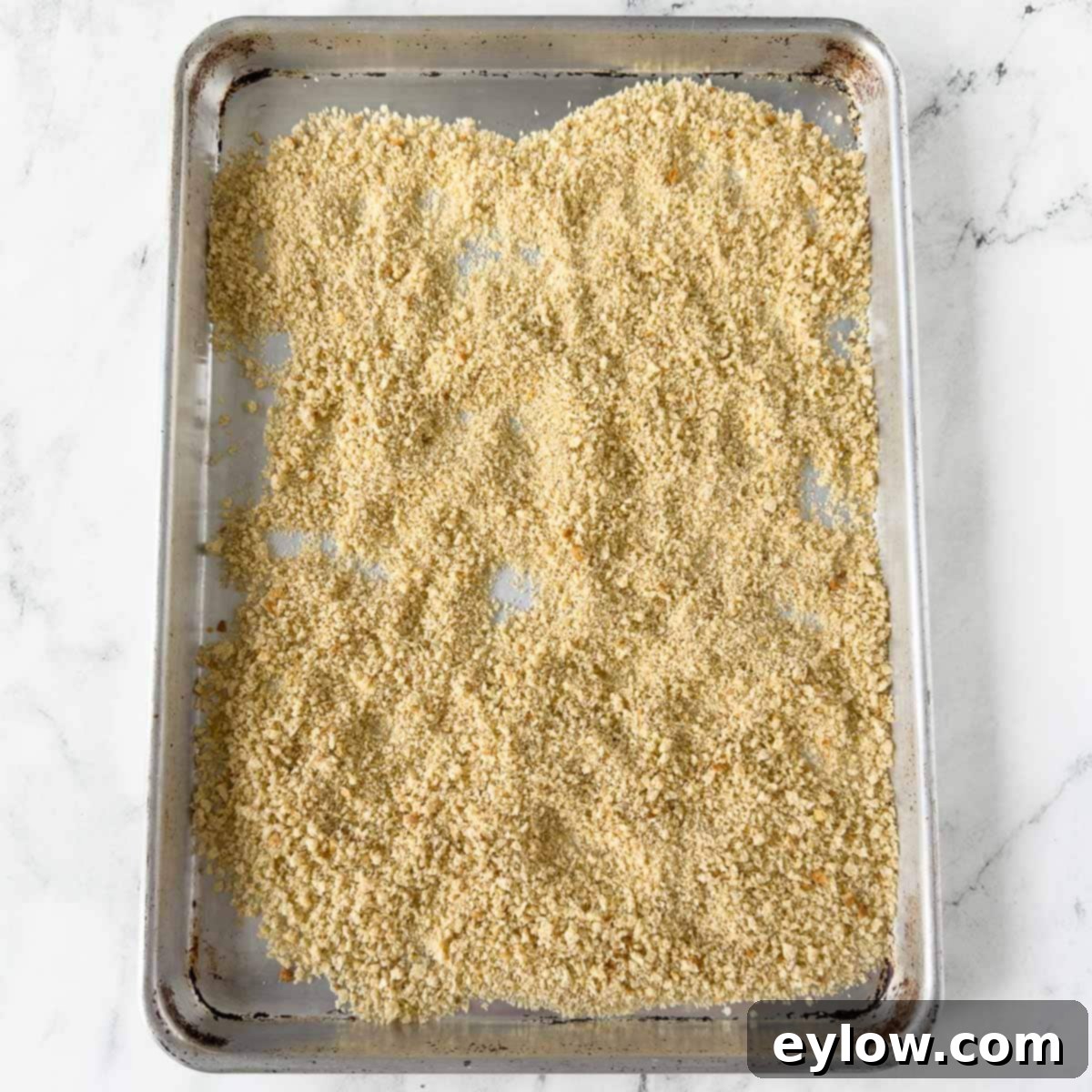 Gluten-free breadcrumbs, fully baked and toasted to a golden perfection, spread on a rimmed baking sheet.