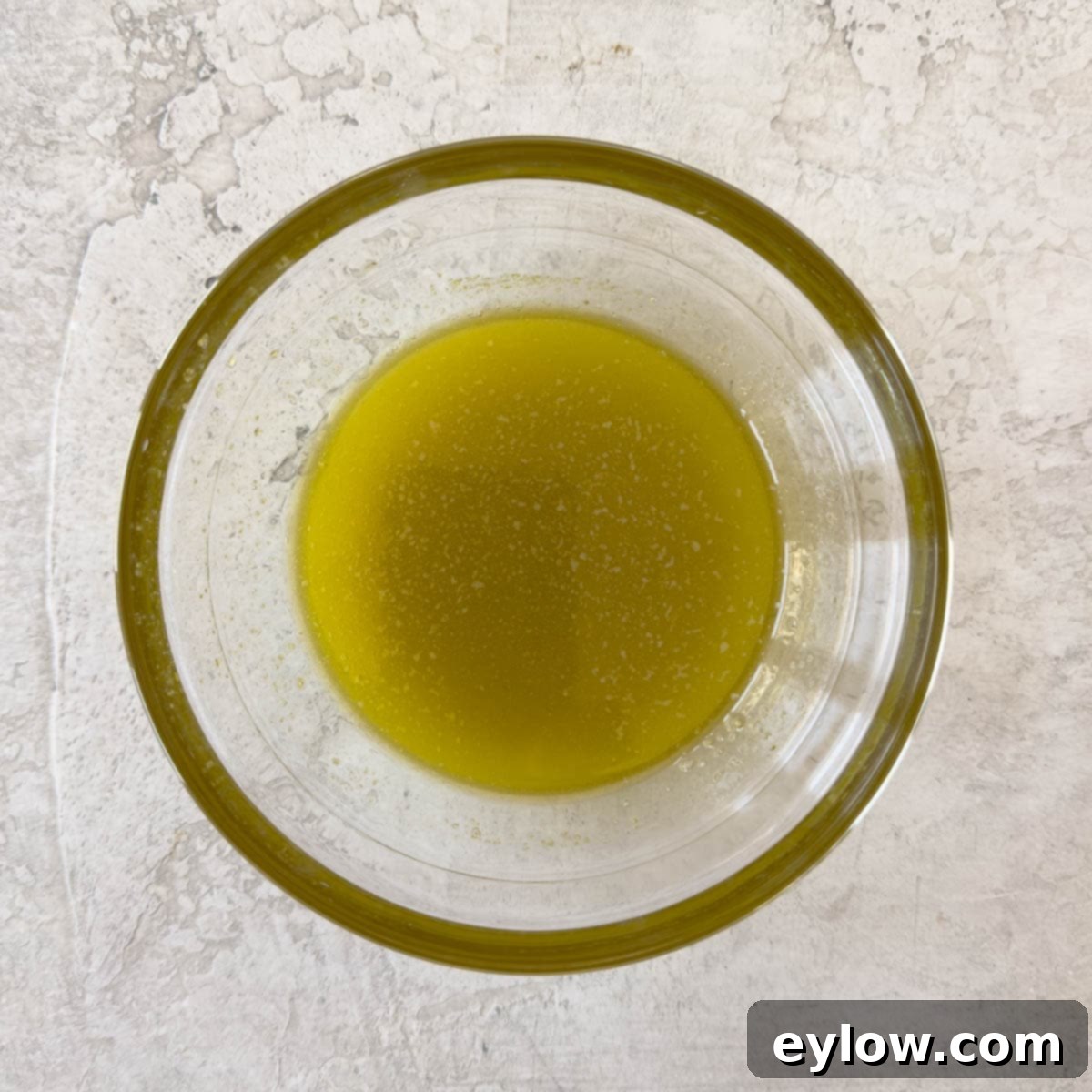 Melted butter, olive oil, and garlic in a small glass bowl.