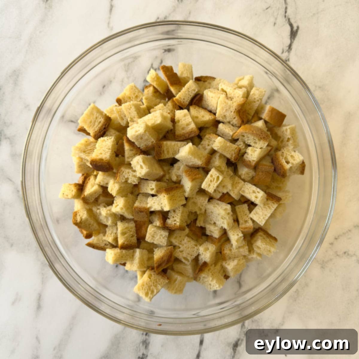 Plain cubes of bread with crusts in a glass bowl for making croutons.