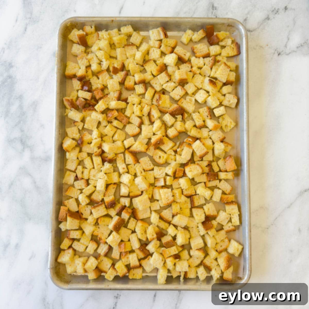 Golden baked bread croutons on a baking sheet with parchment. 