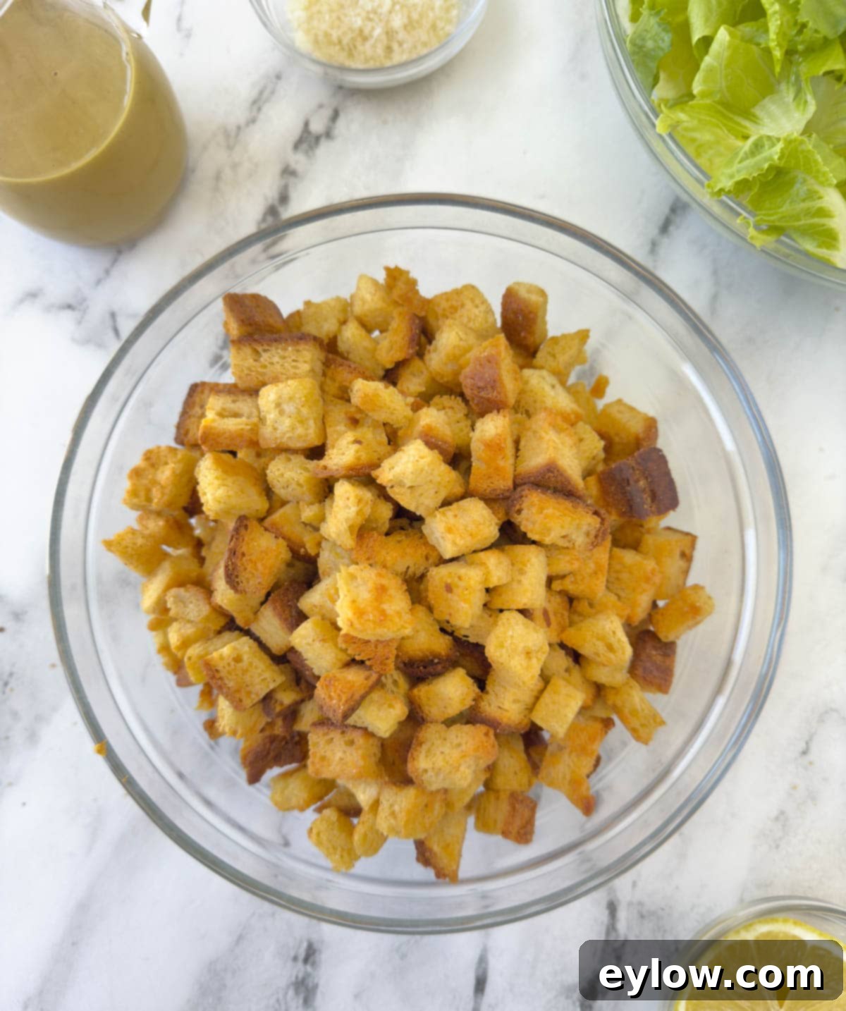 A bowl of golden baked croutons in a glass bowl on a counter.