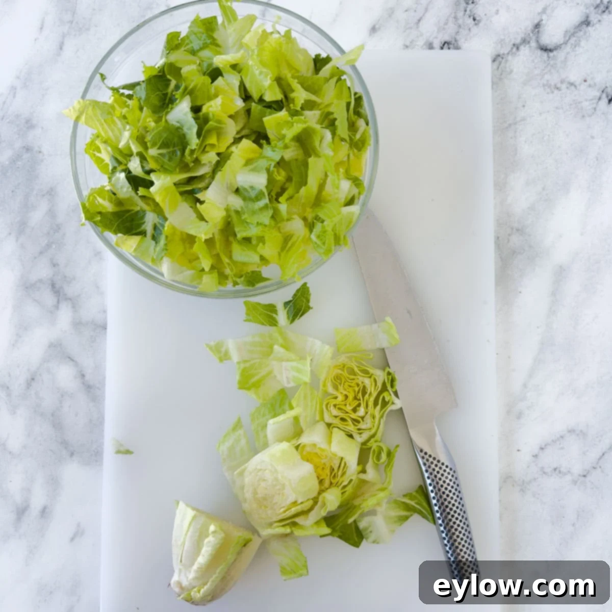 Emperor's Chicken Pasta Salad 7 Chopping romaine leaves for a salad on a white cutting board.