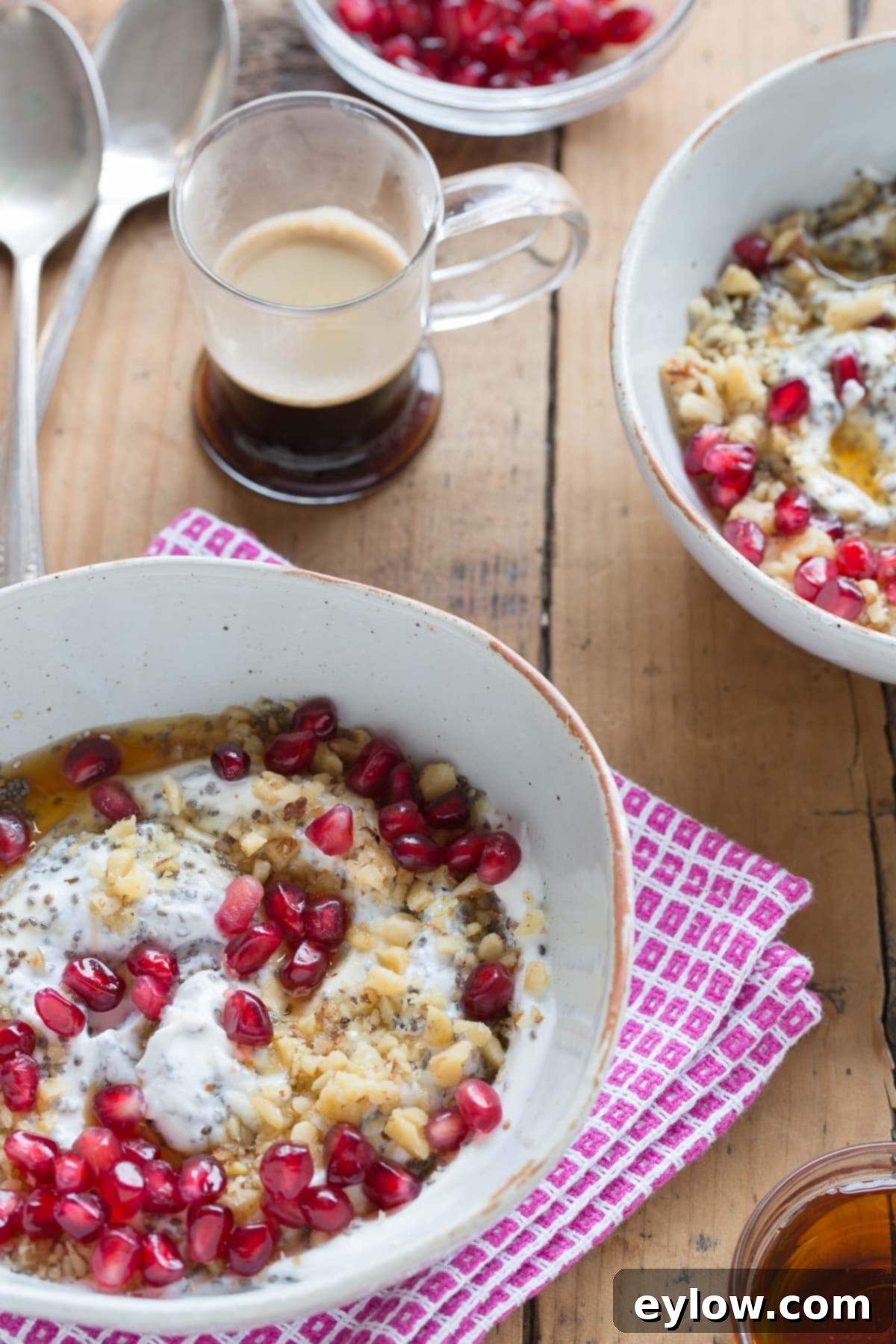 A vibrant Greek yogurt bowl with toppings like red pomegranate seeds, chopped walnuts, and chia seeds.
