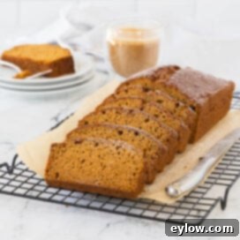 A golden loaf of pumpkin bread sliced and ready to enjoy with coffee.