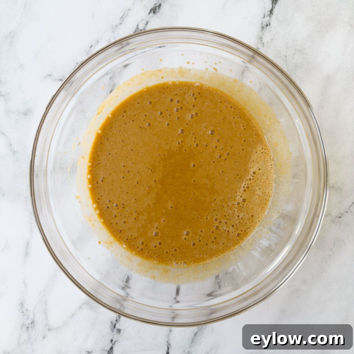 The initial stage of pumpkin bread batter after the wet ingredients have been mixed until perfectly smooth and well emulsified, indicating readiness for the dry components.