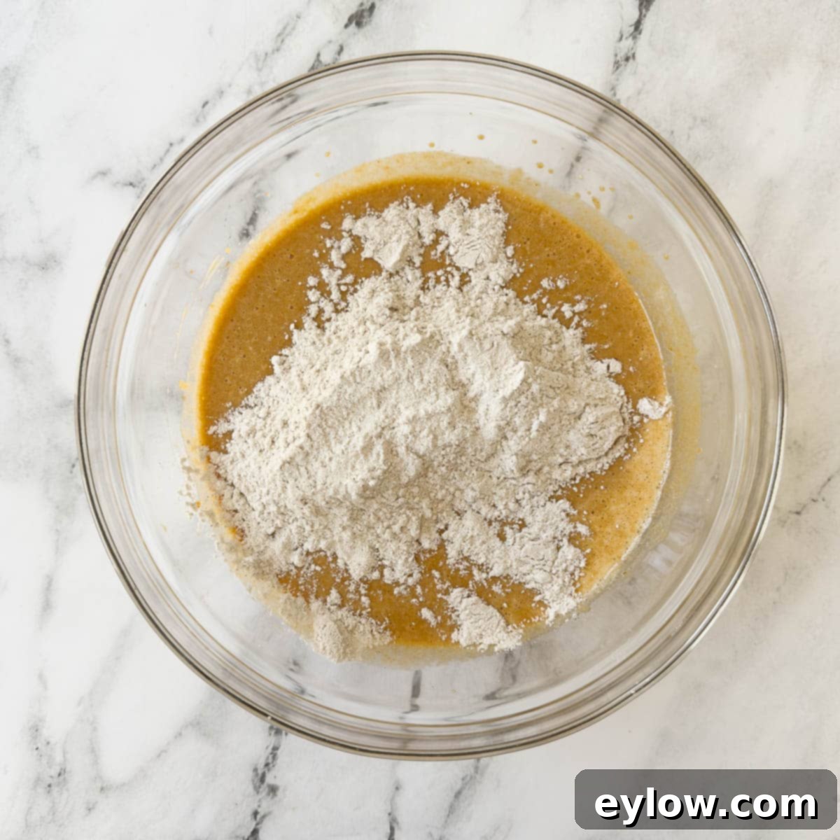 A visual depiction of unmixed dry ingredients in one bowl alongside the smooth, creamy wet ingredients in another, illustrating the next critical step in making delicious pumpkin bread.