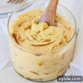 A glass jar of freshly whipped maple butter with maple drizzle and wooden spreader.