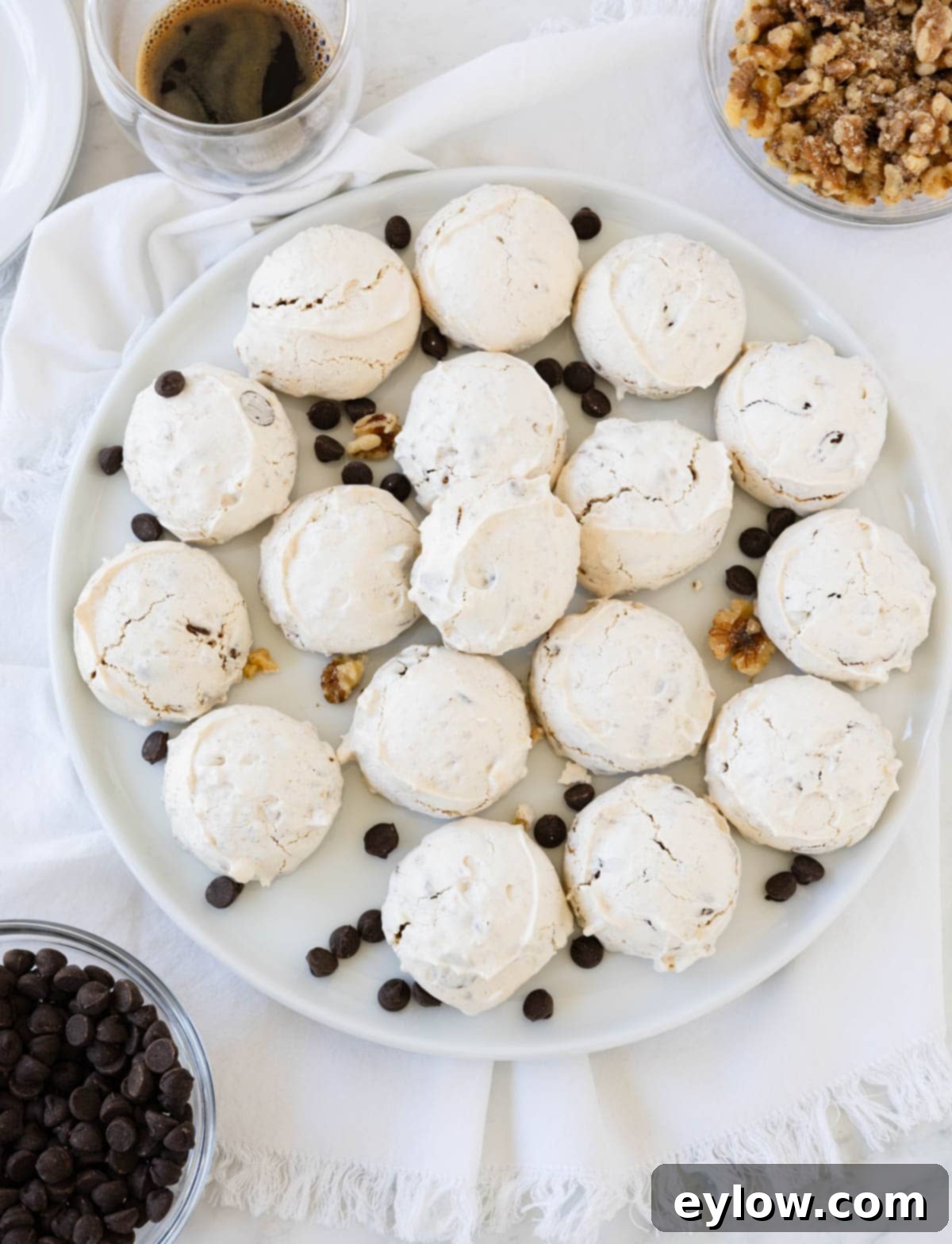 A plate of golden-brown Forgotten Cookies with visible chocolate chips and walnuts on a pristine white serving plate.
