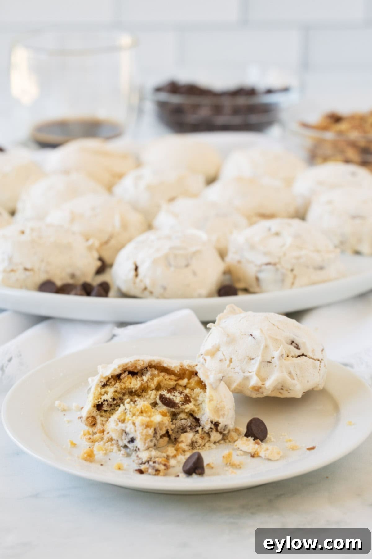 A small white plate displays a whole forgotten cookie and another cookie bitten into, revealing its light, airy interior texture.