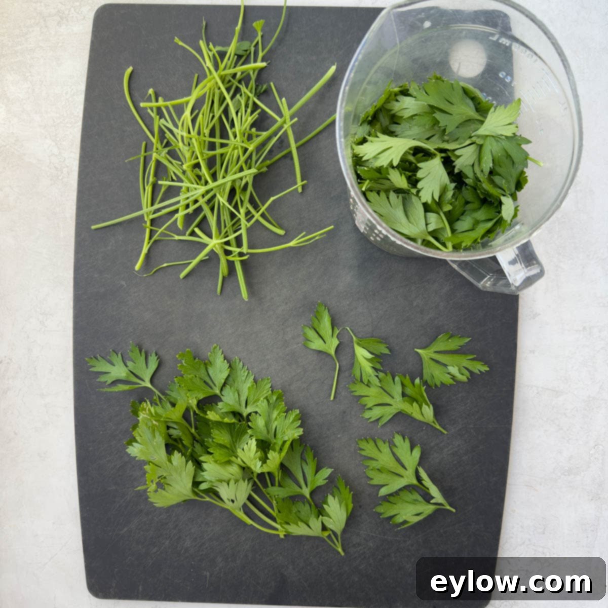 Separating the parsley leaves from the stems on a cutting board.