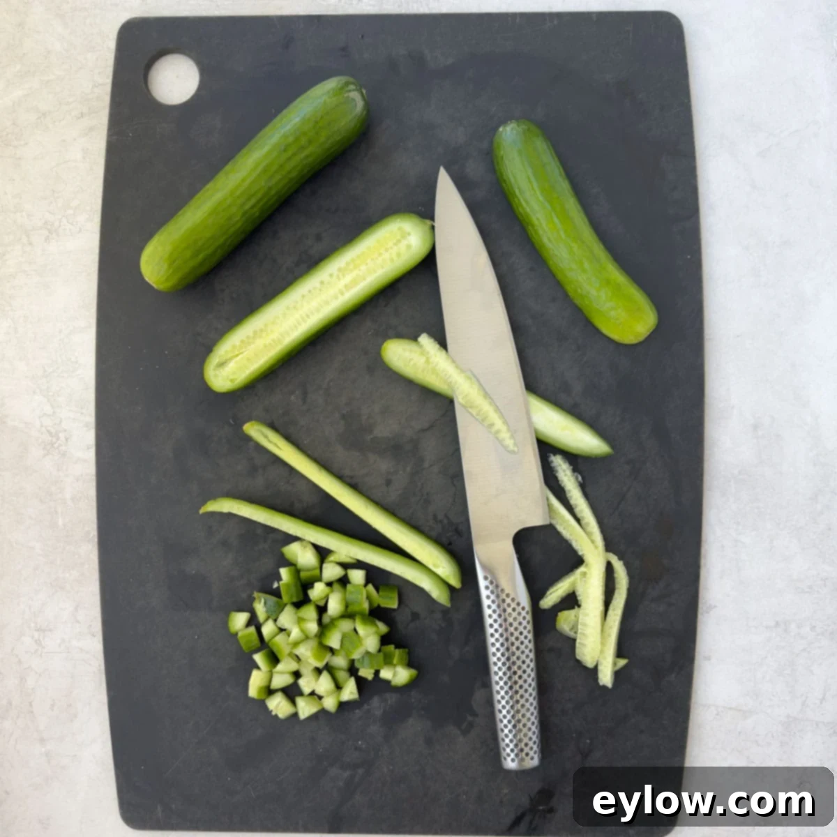 Chopping cucumbers on a cutting board.
