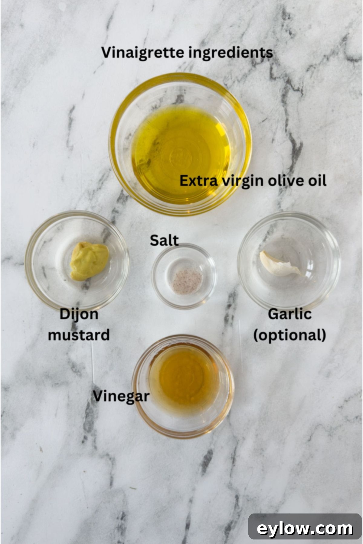 A selection of high-quality ingredients for a vinaigrette salad dressing, including olive oil, various vinegars, and Dijon mustard, laid out on a clean surface.