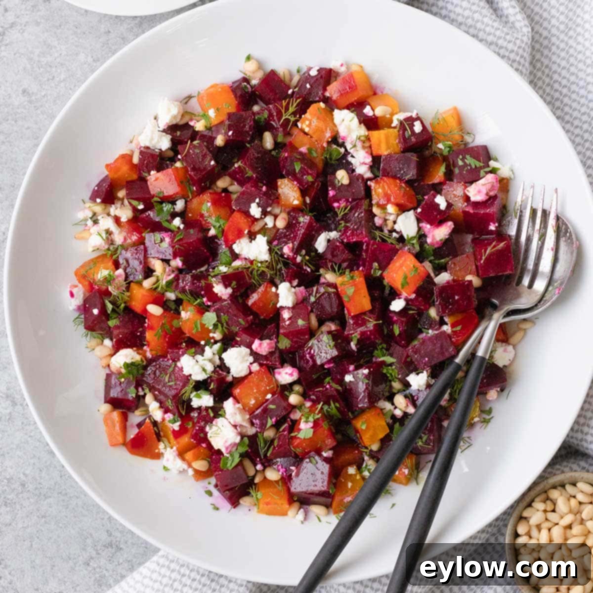 A colorful beet salad featuring deep red and golden roasted beets, tossed with a light vinaigrette, fresh herbs, crumbled feta, and pine nuts in an elegant salad bowl.