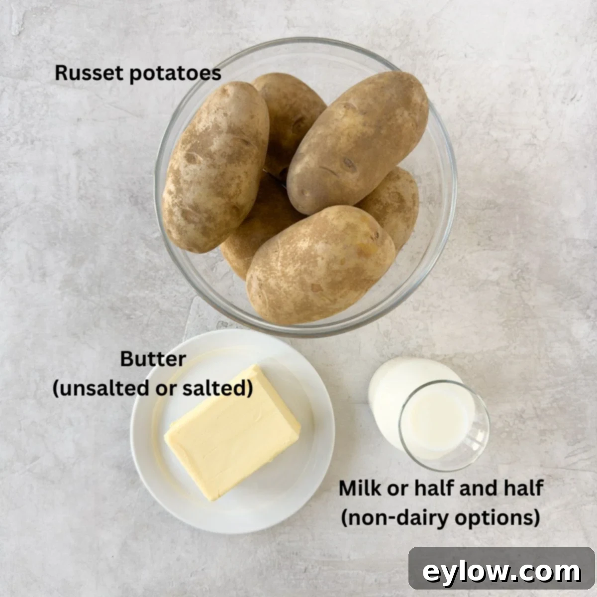 Ingredients for mashed potatoes on the counter with russet potatoes, milk and butter. 