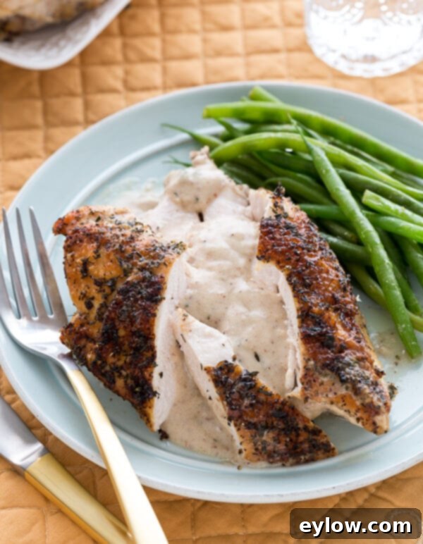 Chicken with gravy on a blue plate for dinner with green beans.