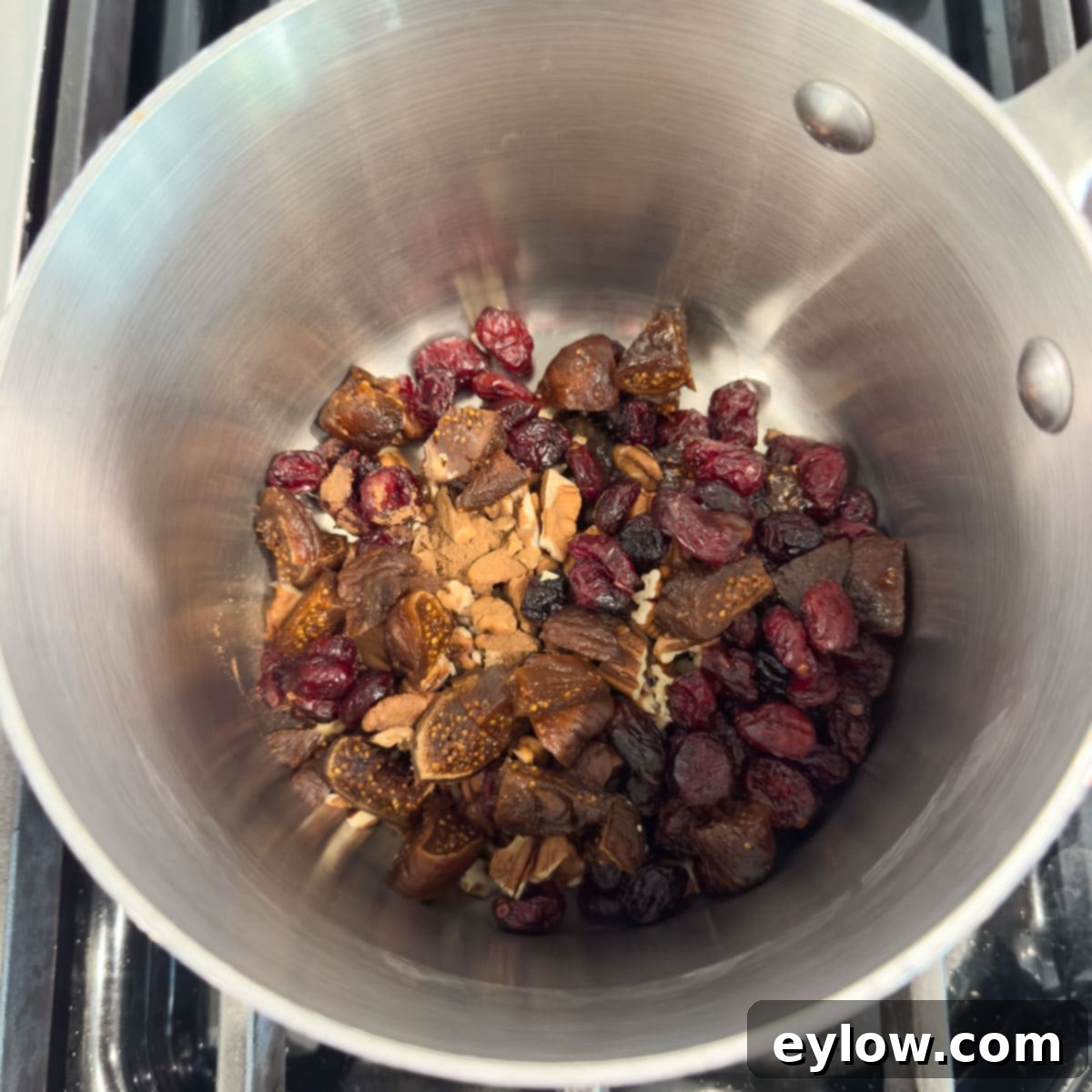 Effortless Baked Brie with Jam 5 Dried cranberries, dried figs, nuts, and spices in a silver pot.