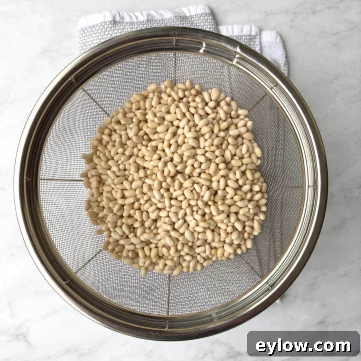 Soaked small white beans, perfectly hydrated, drained in a silver colander.