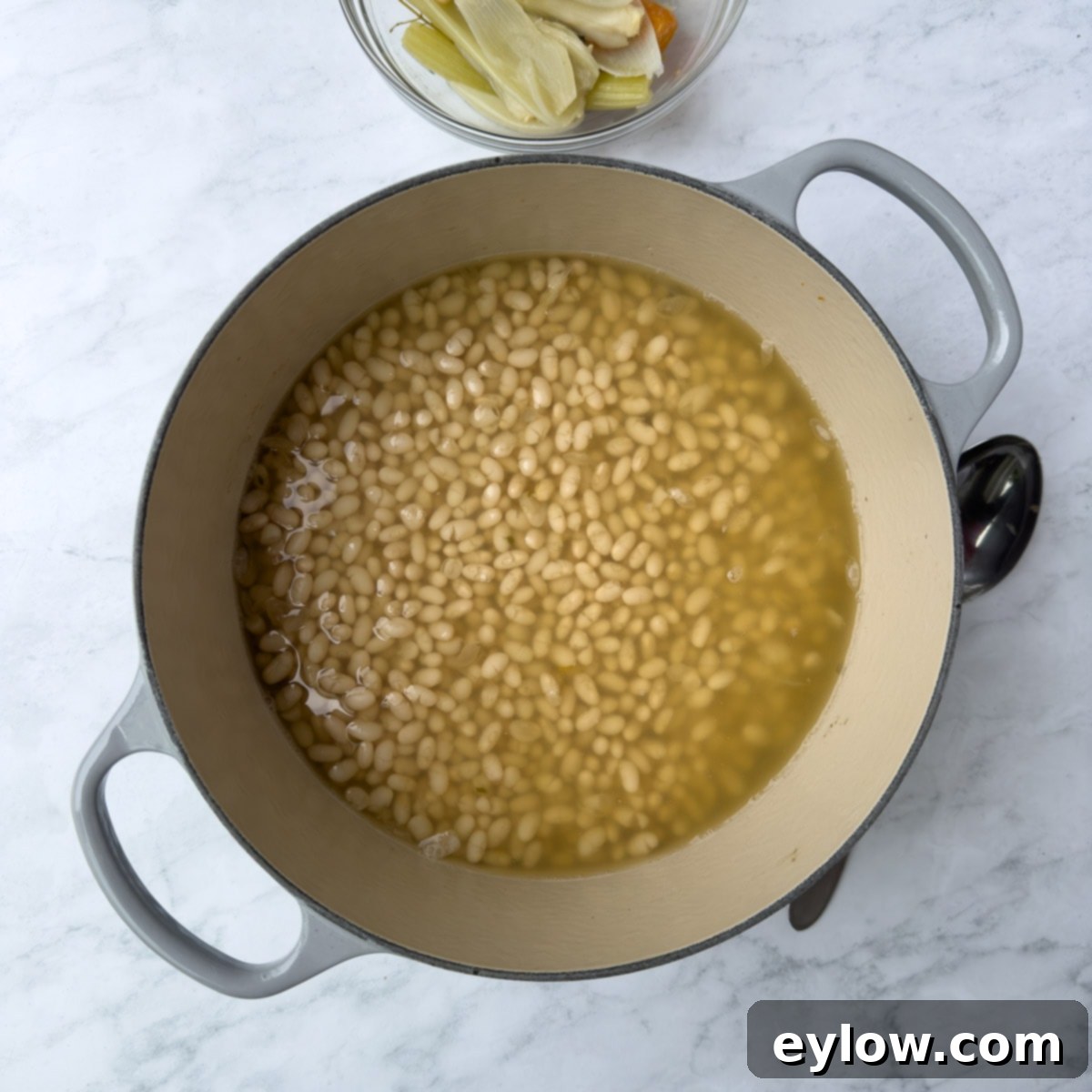 Simmered beans, plump and tender, nestled in a Dutch oven, now ready for the baking process.