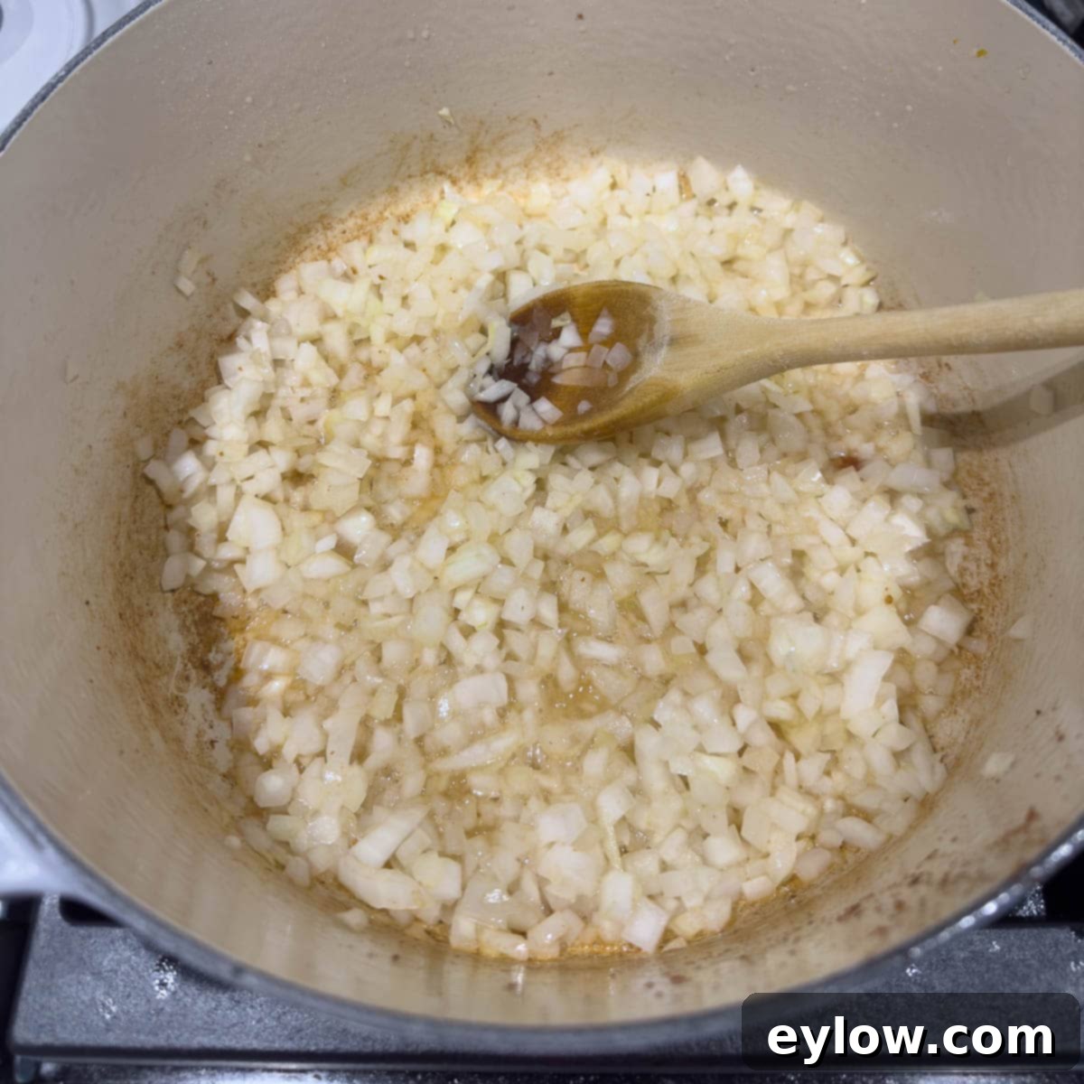 Finely chopped onions sautéing in bacon fat in a heavy pot on the stovetop, turning golden.