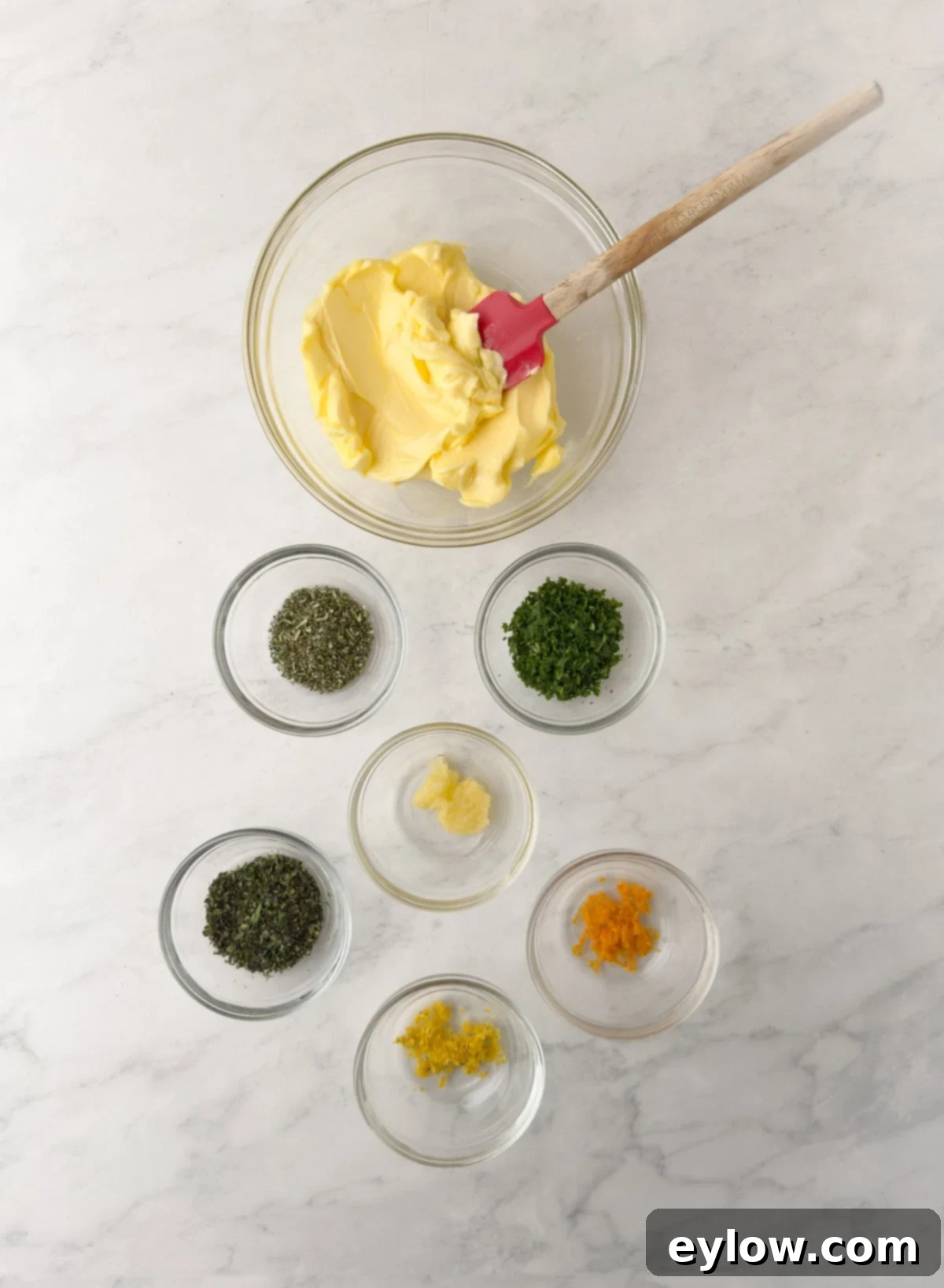 Herbs and butter prepped to make a compound butter in glass bowls.