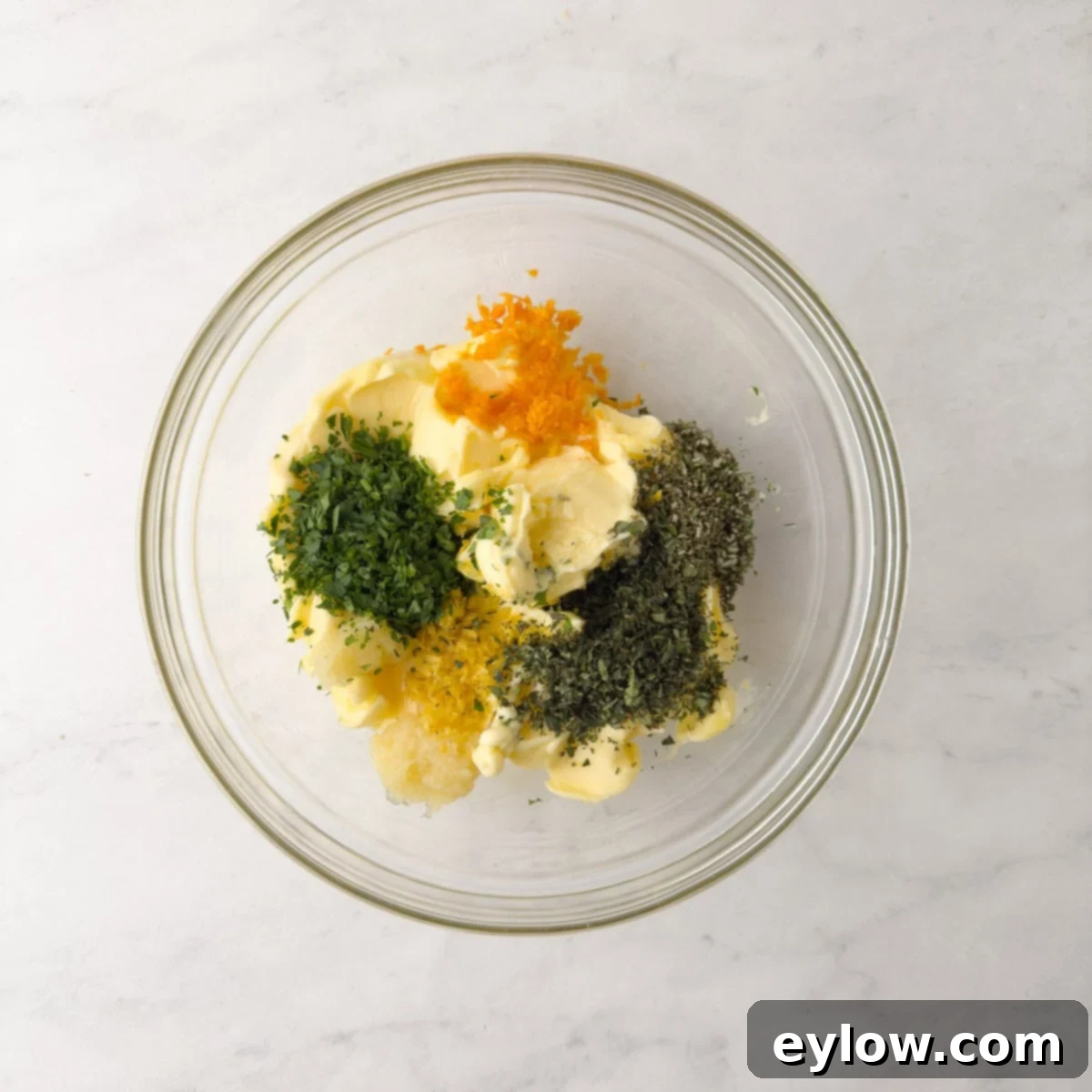 Butter, citrus zest, herbs, and garlic in a glass bowl. 