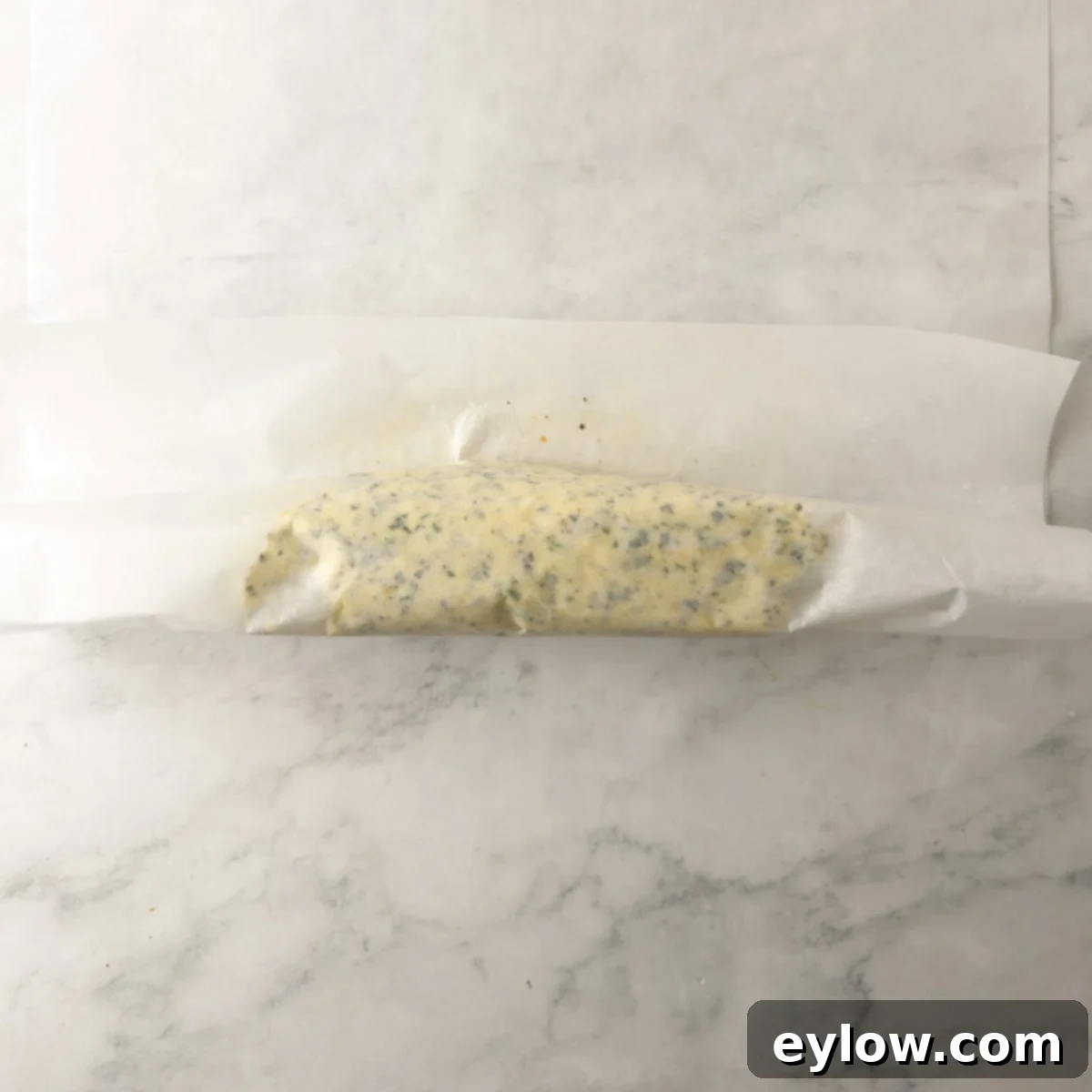 Compound butter in the process of rolling into a log in parchment paper.