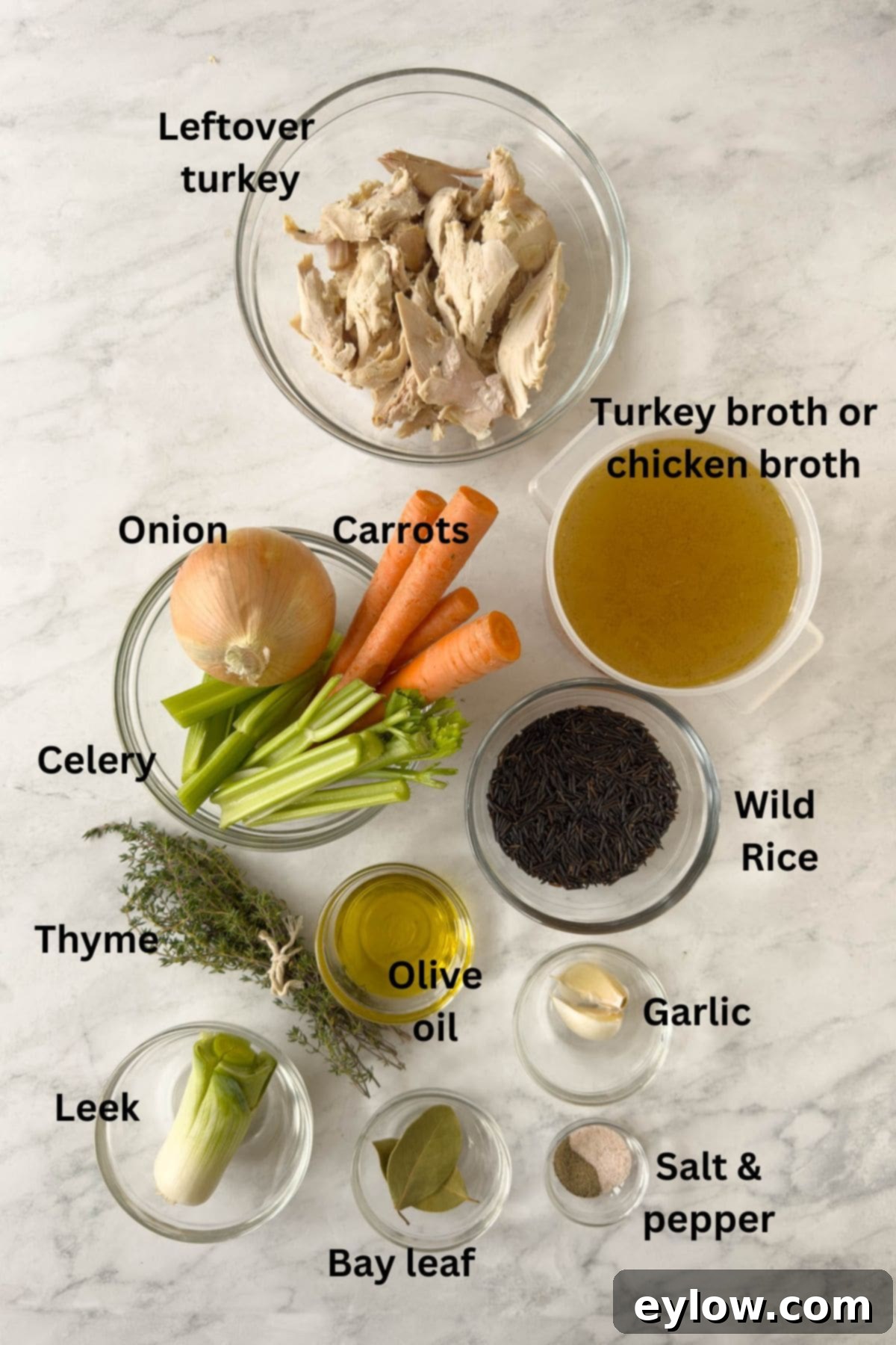 Various fresh ingredients for turkey wild rice soup, including chopped vegetables, turkey, and wild rice, neatly arranged in prep bowls on a kitchen counter.