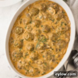 Creamy casserole dish of beef stroganoff made with meatballs with herbs on top.