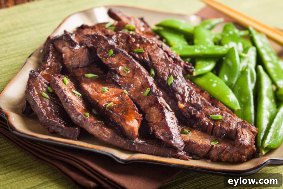 Glazed ginger flank steak stir fry on a plate with green sugar snap peas. 