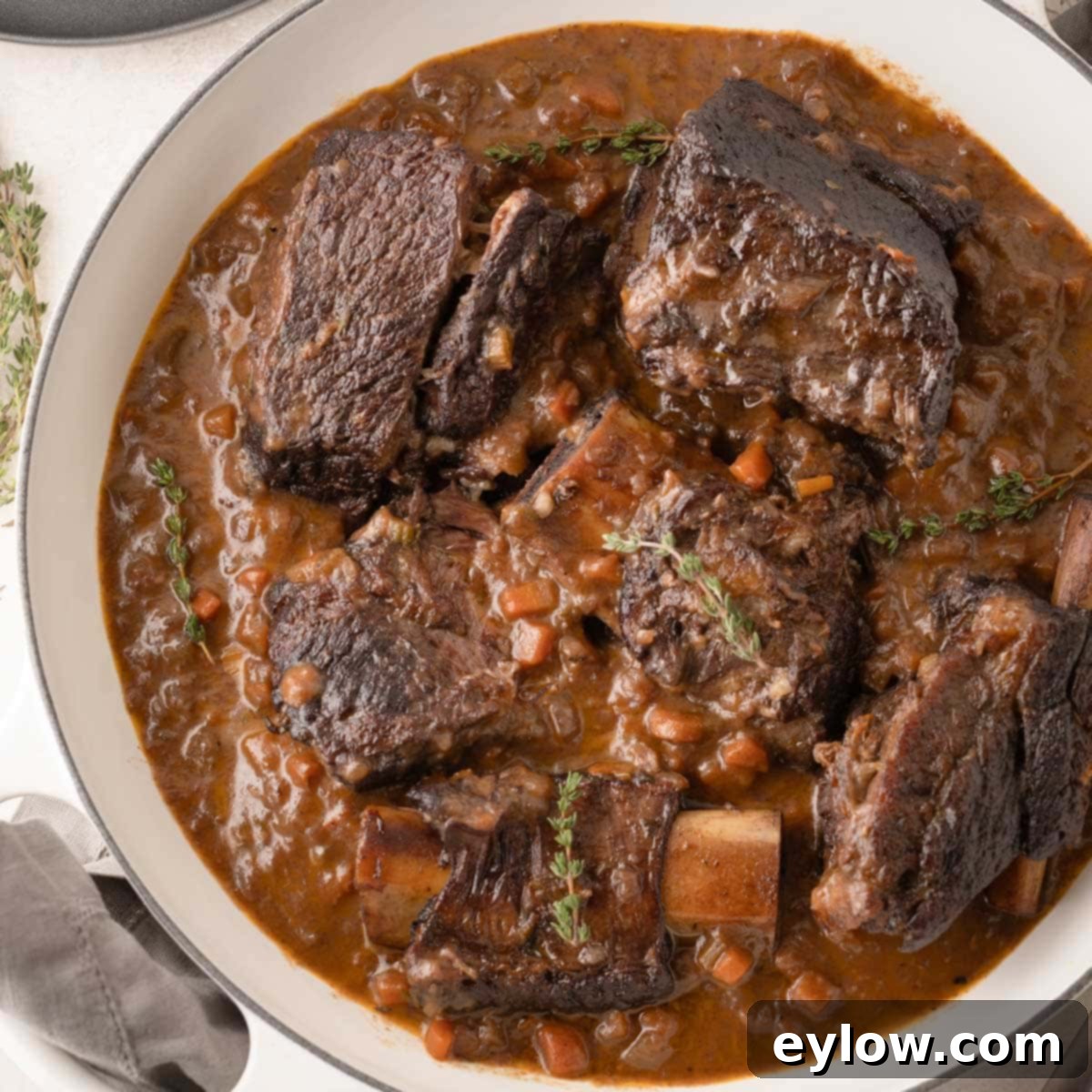 Wine braised beef short ribs with sauce and vegetables in a pan.