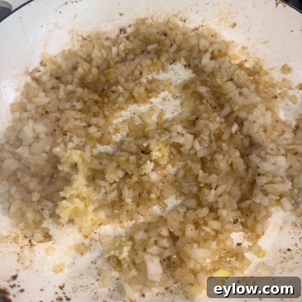Sautéing chopped onions  in a white pan with garlic.