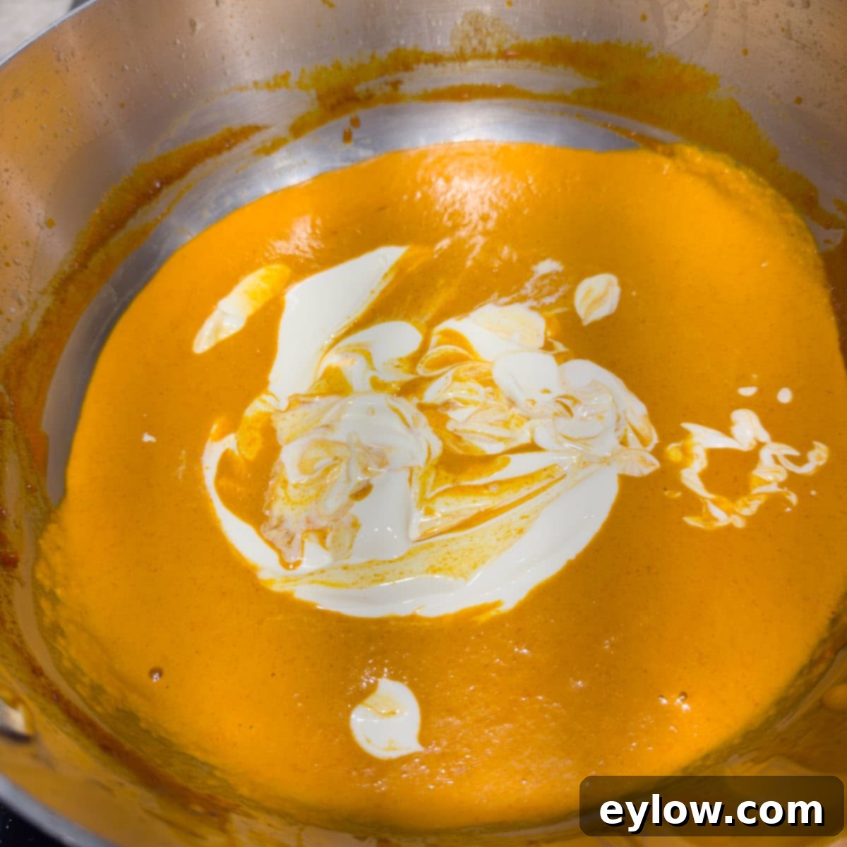 Bright orange paprika sauce adding sour cream to finish.