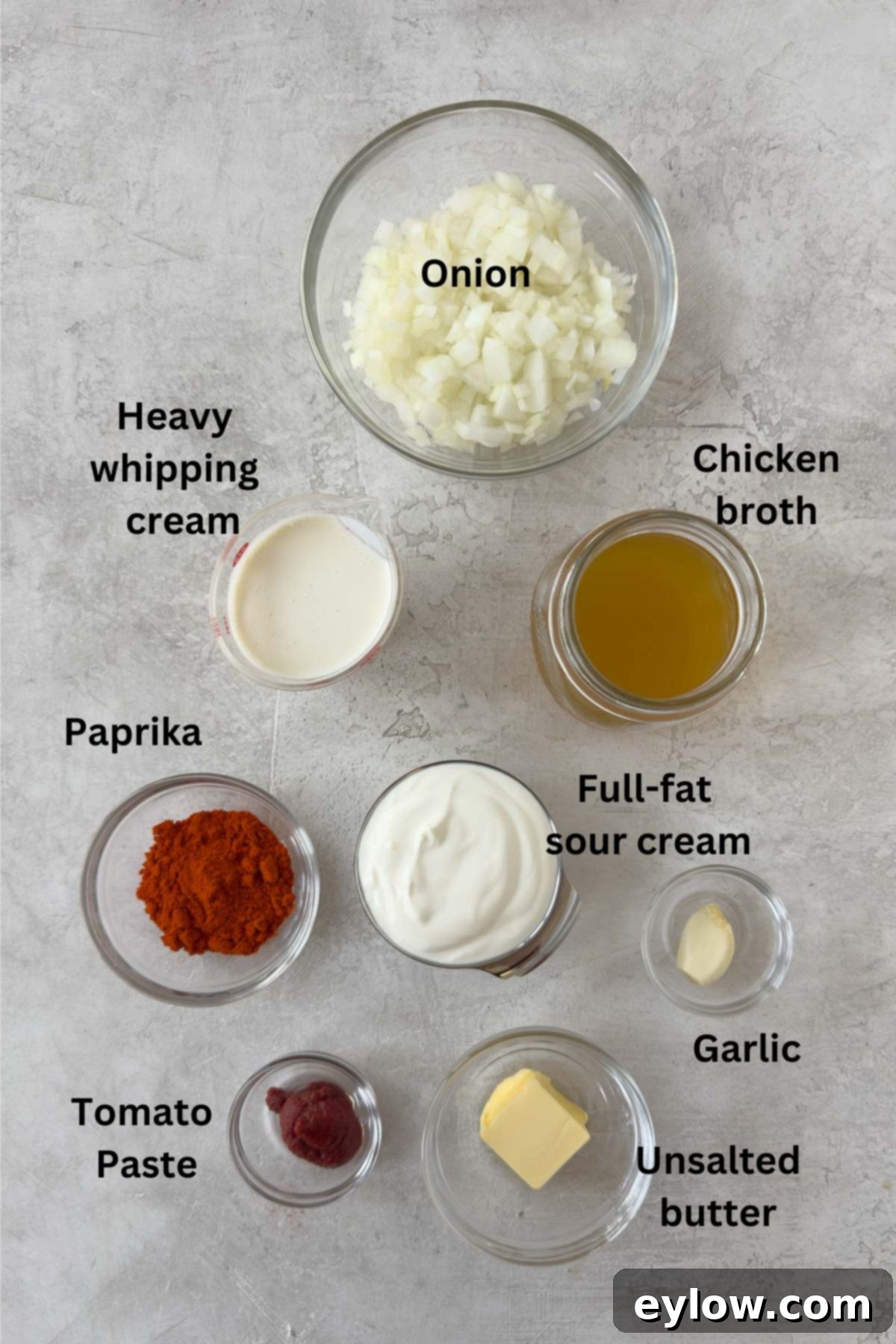 Ingredients for paprika sauce in prep bowls on a gray counter.
