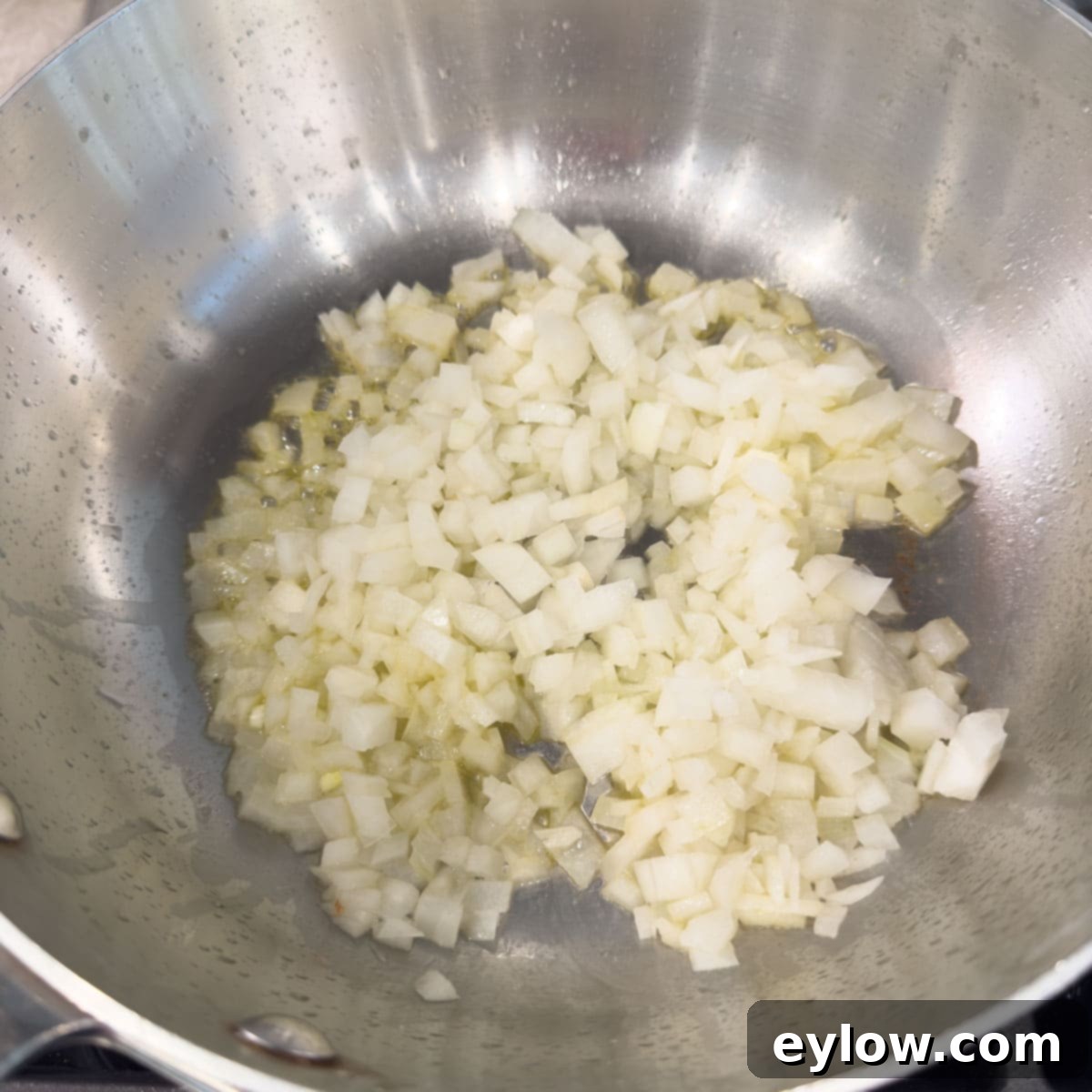 Cooking chopped onions in a stainless steel pan in butter.