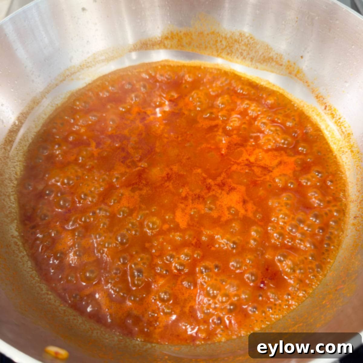 Simmering onions and paprika in a steel pan becoming a sauce.