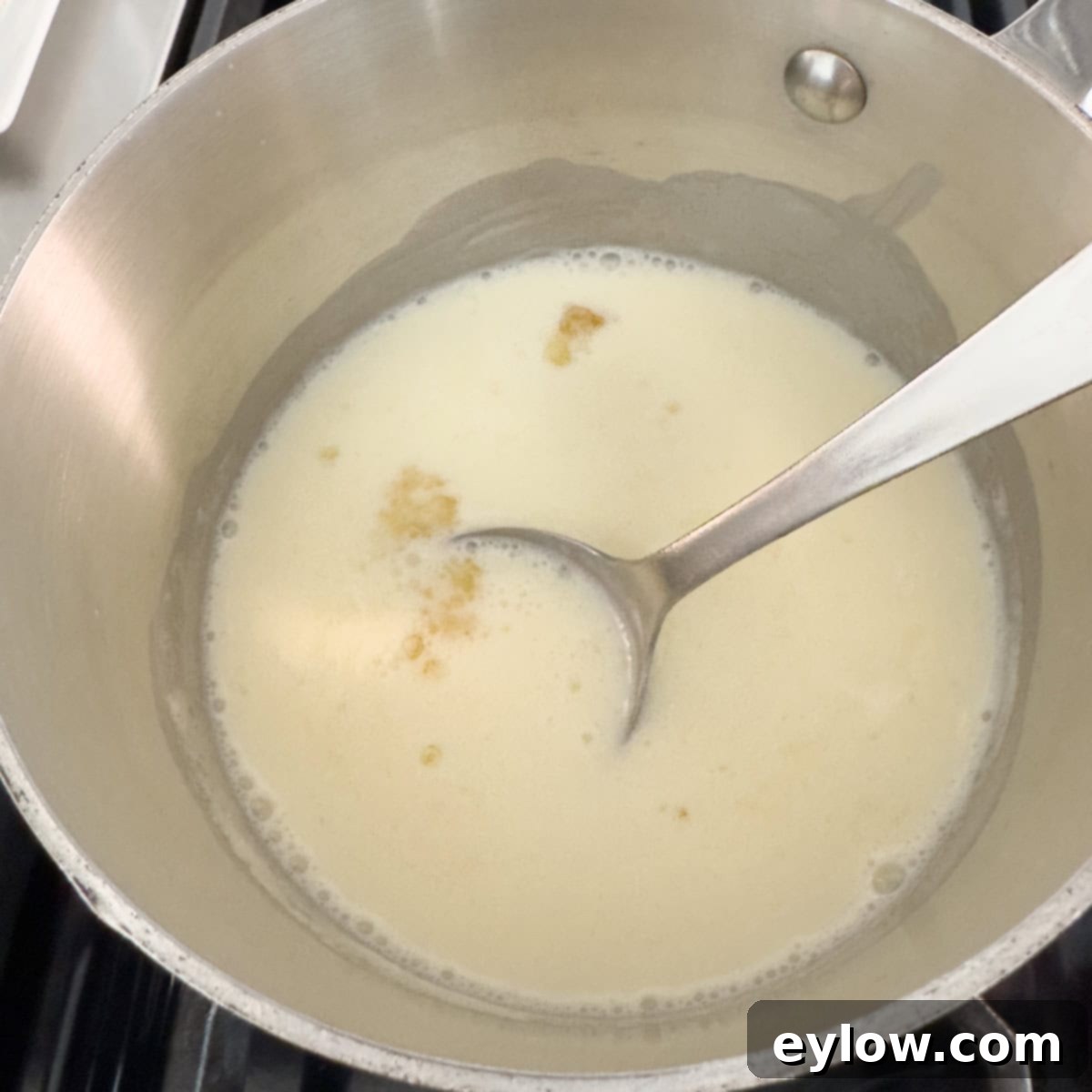 Velvety Strawberry Panna Cotta with Sweet Berry Drizzle 7 Heavy cream in a small pot with a spoon stirring in gelatin.