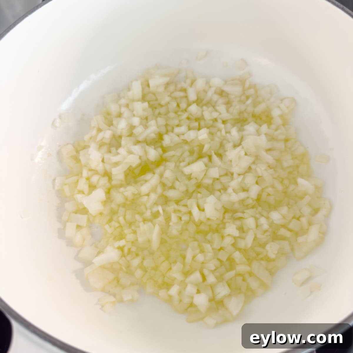 Vibrant Vegetable Rice Medley 4 Sautéing chopped white onion in olive oil in a white dutch oven.