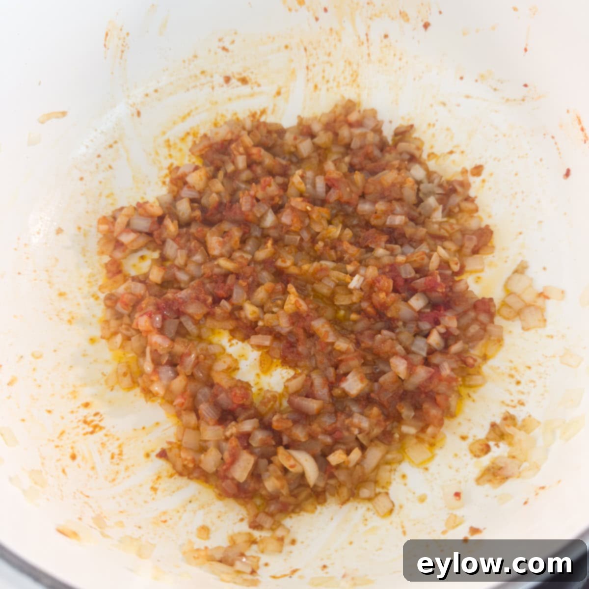Vibrant Vegetable Rice Medley 5 Tomato paste stirred into white rice turning it red in a pot.