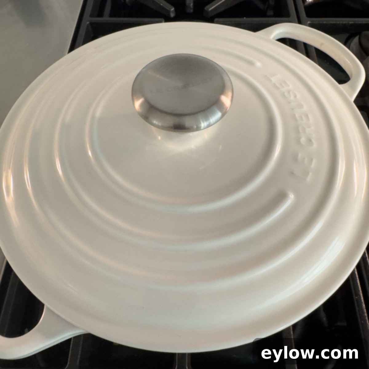 Vibrant Vegetable Rice Medley 8 A white dutch oven with a silver top handle with the lid on the stove.
