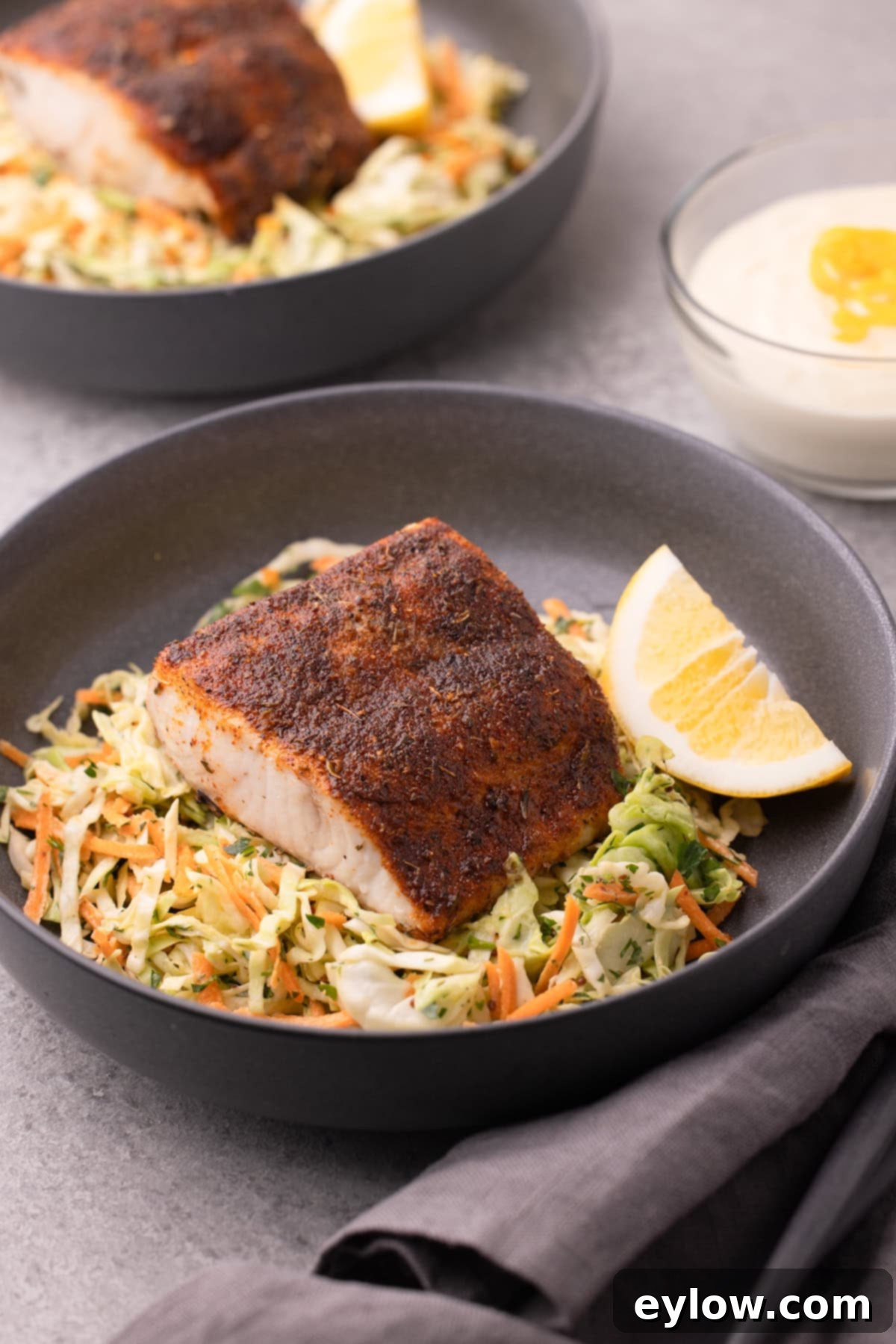 Crispy Blackened Mahi Mahi in the Air Fryer 2 A shallow gray bowl of colorful coleslaw and blackened mahi mahi filet with lemon wedge.