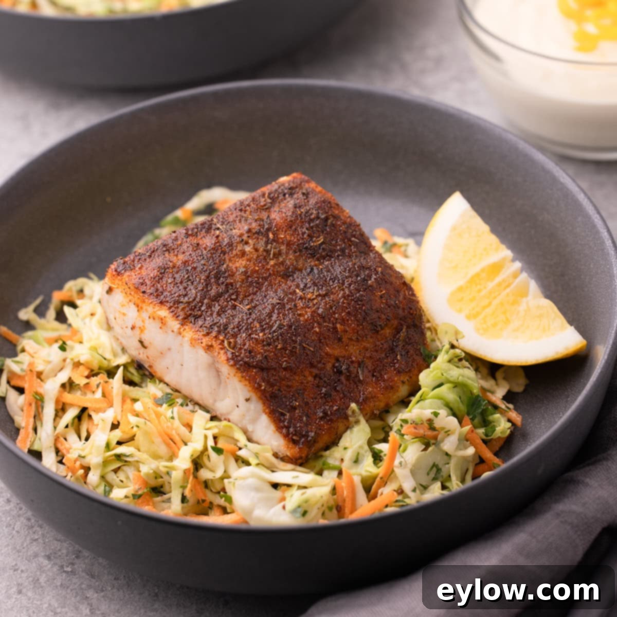Crispy Blackened Mahi Mahi in the Air Fryer 8 A shallow gray bowl with coleslaw topped with air fryer mahi mahi with a blackening seasoning.