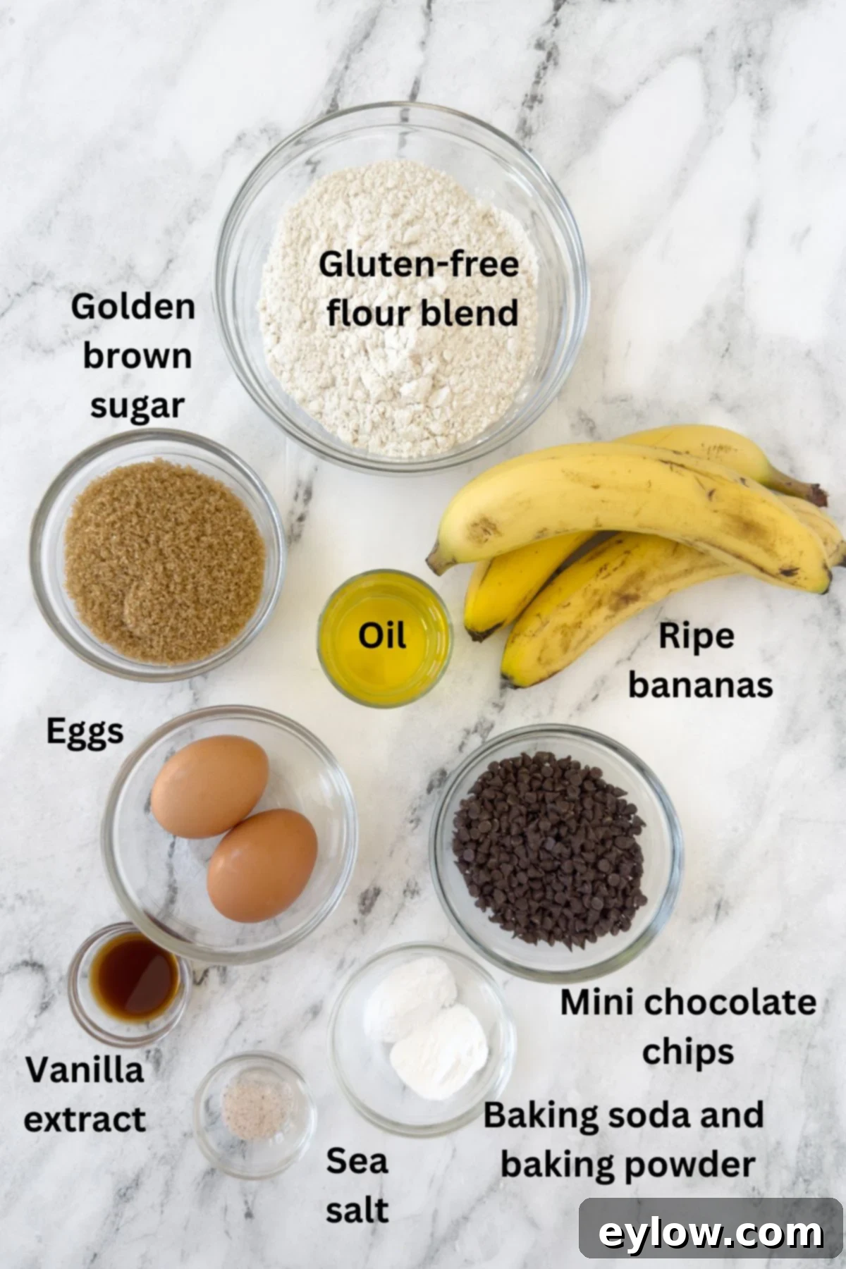 Carefully arranged ingredients for gluten-free chocolate chip banana muffins laid out on a clean marble counter, highlighting the fresh bananas, flour, and chocolate chips.