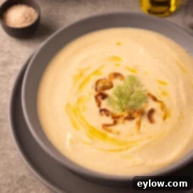 Velvety Fennel and White Bean Soup 7 A gray bowl of fennel and white bean soup with olive oil and fried shallots.