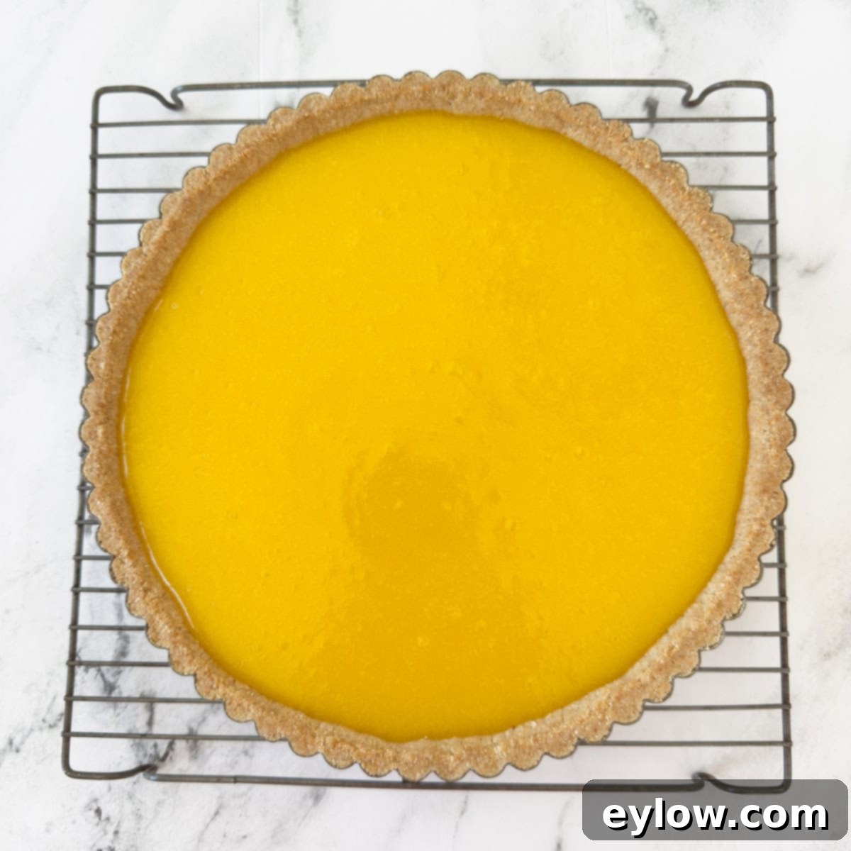 Zesty Lemon Meringue Tart 9 Baked lemon curd tart cooling on a wire rack on the counter.