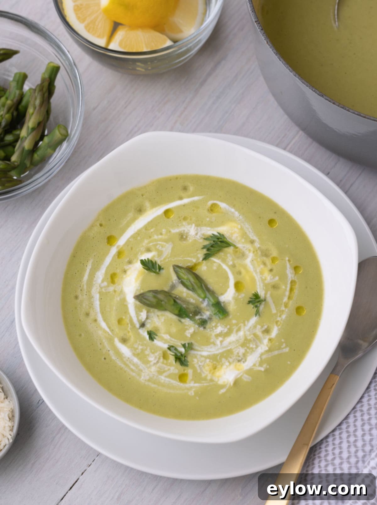 Beautiful green asparagus soup in a white bowl with tasty garnishes, ready to be served on a dinner table.
